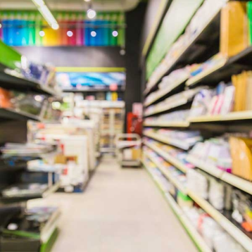 Blurred view of a stationery or DIY aisle in a retail store, colourful signage in background
